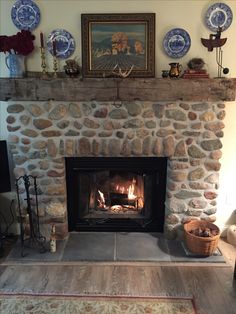 a stone fireplace with plates on the mantle