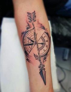 a compass with an arrow tattoo on the arm