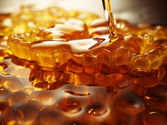 honey syrup being poured on top of some ice cubes in an orange liquid filled bowl