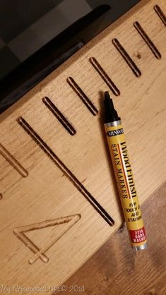 a pen sitting on top of a piece of wood next to some screws and nails