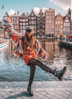 a woman is posing on the edge of a body of water with her legs spread out