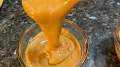 caramel sauce being drizzled over the top of two glass bowls on a granite countertop