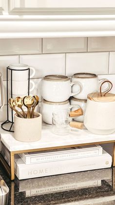 the kitchen counter is filled with coffee cups and mugs on top of cookbooks