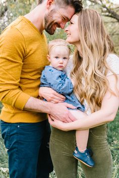 a man and woman holding a baby in their arms while standing next to each other