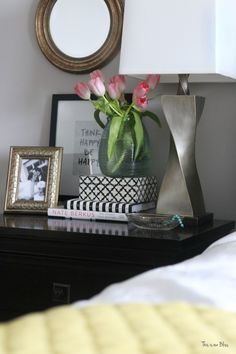 a vase with pink flowers sitting on top of a table next to a framed photo