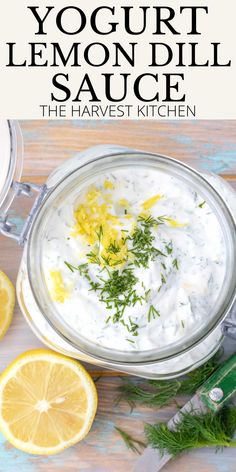 yogurt lemon dill sauce in a glass bowl with sliced lemons on the side