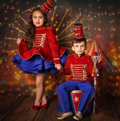 two children dressed in red and blue are posing for a photo with fireworks behind them