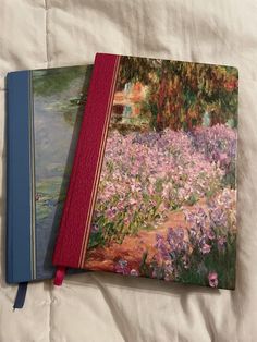 two books are sitting on a bed with white sheets and pink flowers in the background