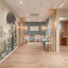 an empty room with chairs and tables in front of a wall painting on the wall