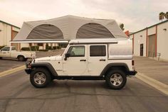 a white jeep parked in front of a building with an awning on it's roof