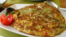 an omelet is on a white plate with red peppers and a fork next to it