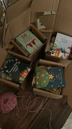 several boxes filled with christmas cards sitting on top of a wooden table next to a red and white twine