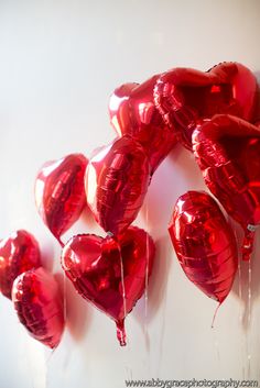 red heart shaped balloons are hanging on the wall