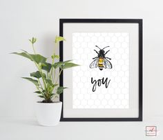 a bee is sitting on the wall next to a potted plant and a framed poster