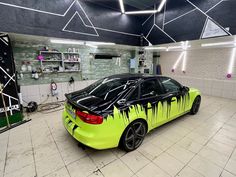 a neon green sports car parked in a garage with graffiti on the hood and windows