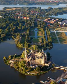 an aerial view of a castle in the middle of a lake with lots of trees around it