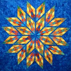 a blue quilt with an orange, yellow and red star design on the center piece