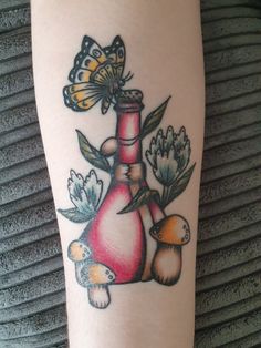 a woman's arm with a bottle and mushrooms tattoo design on the left leg