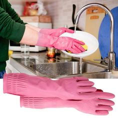 a person wearing pink gloves washing dishes in a kitchen