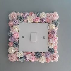 a light switch cover decorated with pink, blue and white flowers on a gray wall