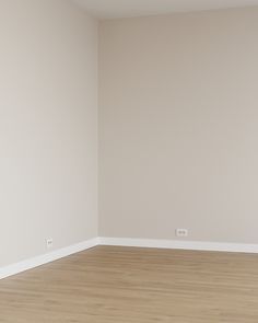 an empty room with hard wood floors and white walls, painted in pale beige tones