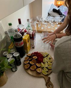 a woman standing in front of a counter filled with drinks and fruit on top of it