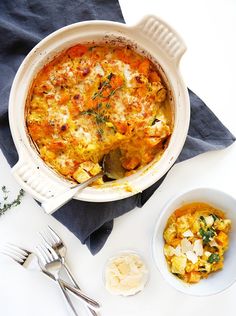 a casserole dish with carrots and cheese in it next to silverware