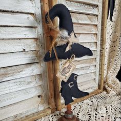 a pair of black boots hanging from a hook on a wooden stand next to a white wall