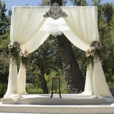 an outdoor ceremony setup with white drapes and flowers