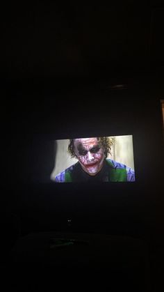 a television screen with the joker on it's face is lit up in the dark