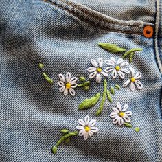 some white flowers are embroidered on the back of someone's jean pants and jeans