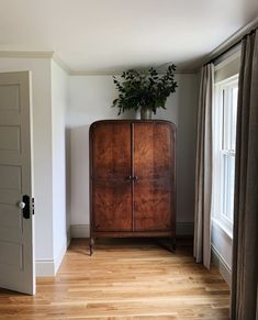 a wooden cabinet sitting in the corner of a room next to a door and window