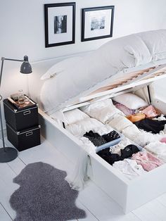 an open white shoe box sitting on top of a floor next to a lamp and pictures