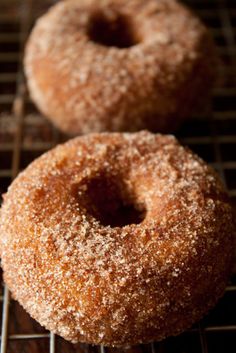 two sugared donuts sitting on top of a cooling rack next to each other