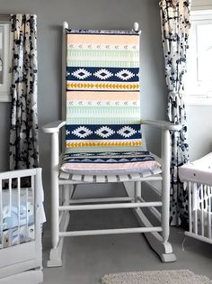 a white rocking chair sitting next to a baby crib in a room with curtains