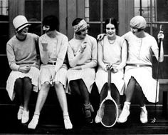 an old black and white photo of four women sitting on steps with tennis rackets