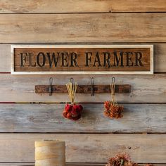 a sign that says flower farmer hanging on a wall next to two vases filled with flowers