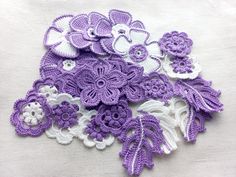 purple and white crocheted flowers are displayed on a tablecloth, with one flower in the center