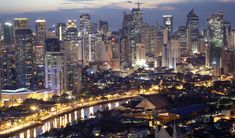 the city is lit up at night with lights on and buildings in the foreground