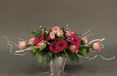 a vase filled with pink and red flowers on top of a gray table next to a wall