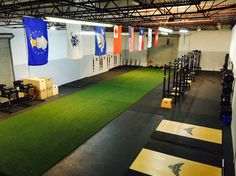 an indoor gym with green carpet and blue flag banners on the wall behind it, along with rows of exercise equipment