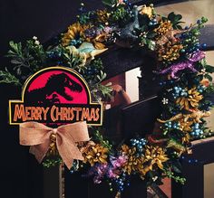 a wreath with the words merry christmas and a t - rex on it is hanging in front of a door