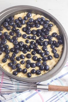 a blueberry cake in a pan with a whisk on the side next to it