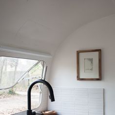 a kitchen sink with a black faucet and white tiled walls in the background