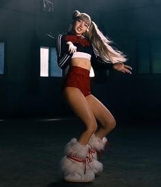 a woman in red and white is dancing with her legs spread out, while wearing furry boots