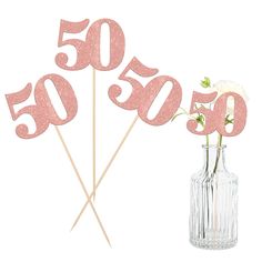 there is a vase with some flowers in it and the number 50 on sticks next to it