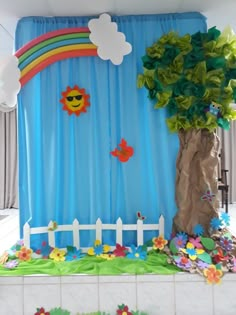 a blue backdrop with flowers and a tree in the middle is decorated like a rainbow