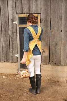 a woman standing in front of a wooden fence with a yellow bow on her back