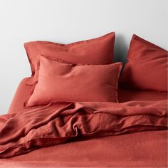 a bed with red sheets and pillows on it