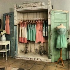 an old wooden cabinet with dresses hanging on it's sides and two mannequins in the background